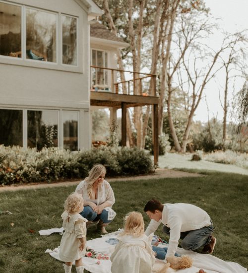 A family practicing gentle parenting while playing on the grass in front of a house.